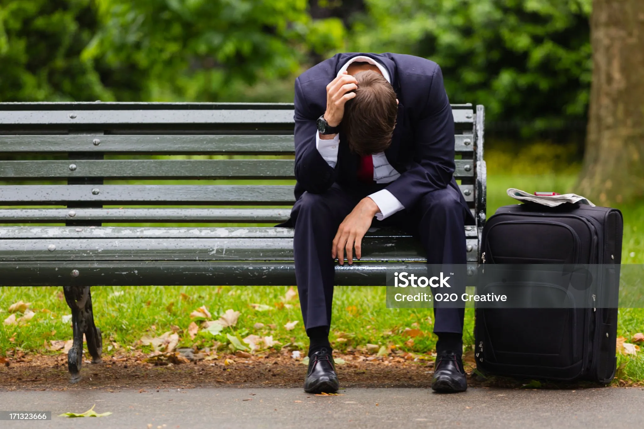 A tired businessman on a bench getting some fresh air.