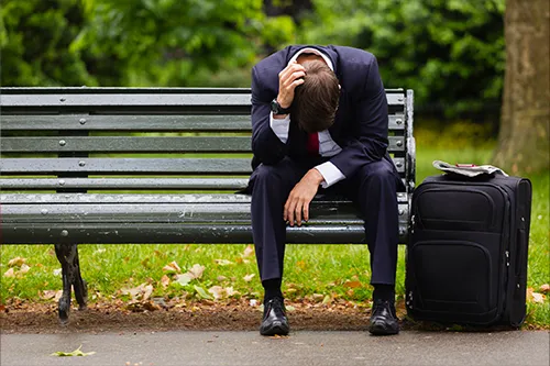 A tired businessman on a bench getting some fresh air.