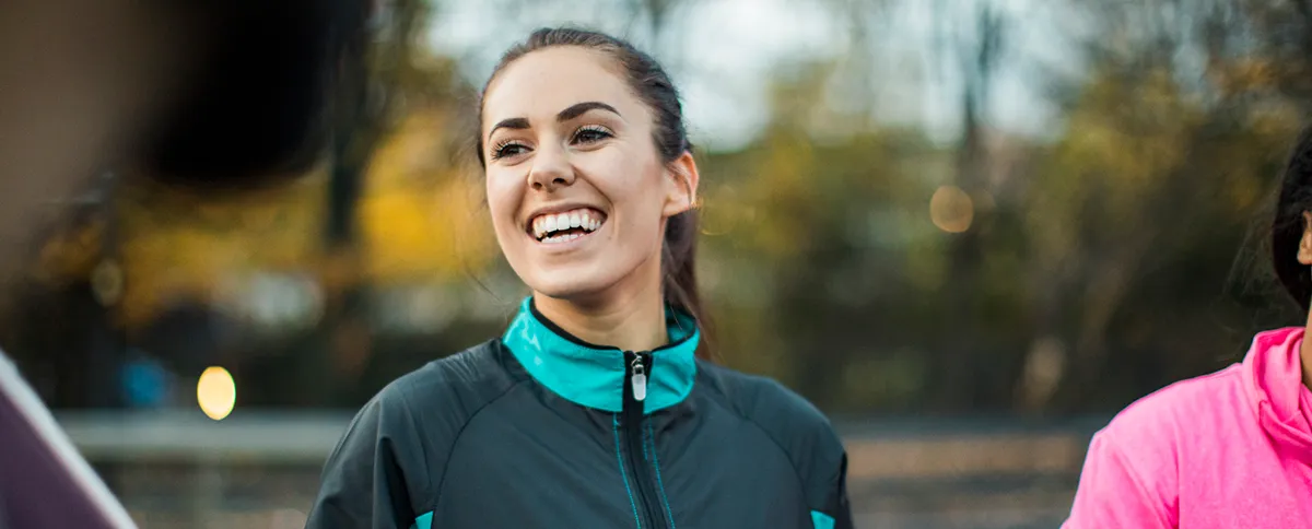 A young woman rests from her run with a running group.